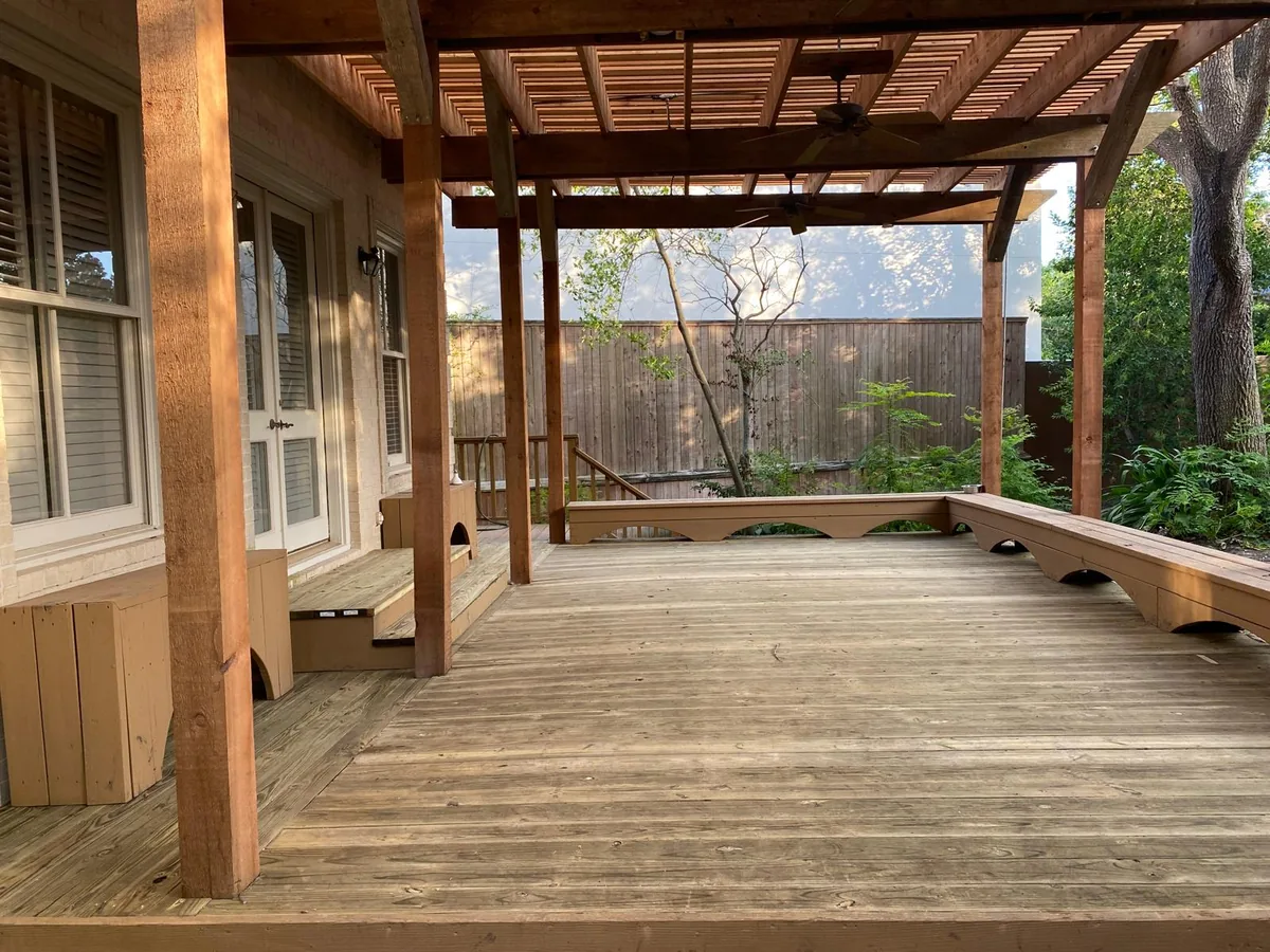 Wood deck with a pergola cover overhead supported by stained wood posts and beams