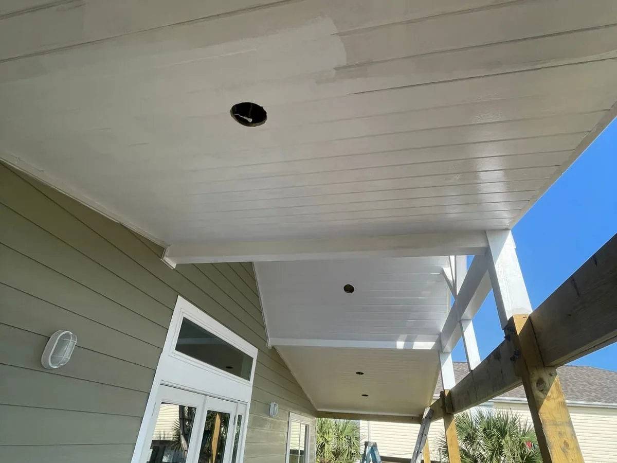 Covered porch ceiling finished in white tongue and groove boards