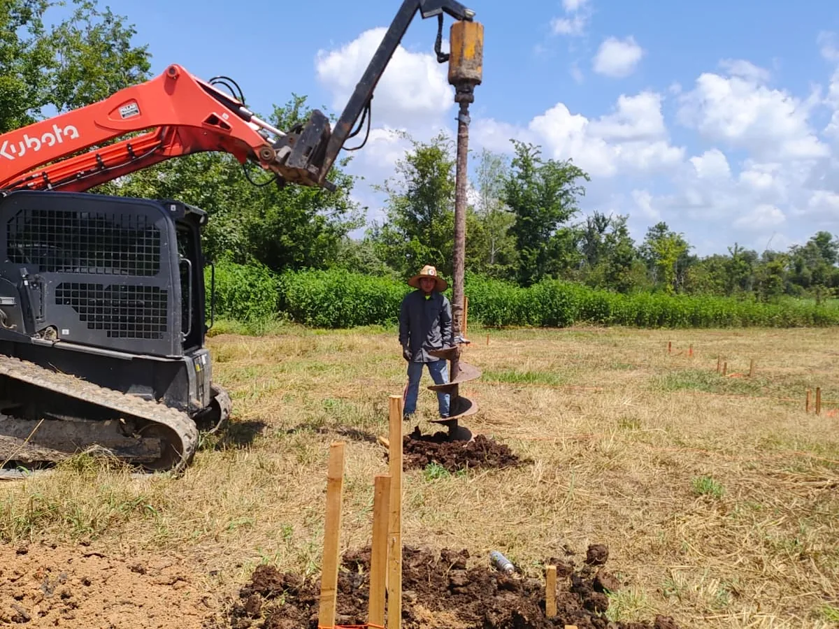 Track loader with an auger attachment drilling foundation pier holes