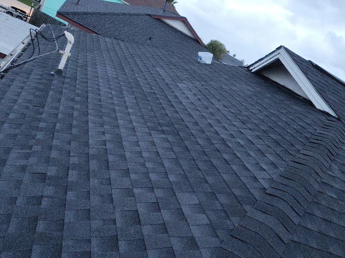 Gray architectural shingle roof with dormers and white trimmed gables