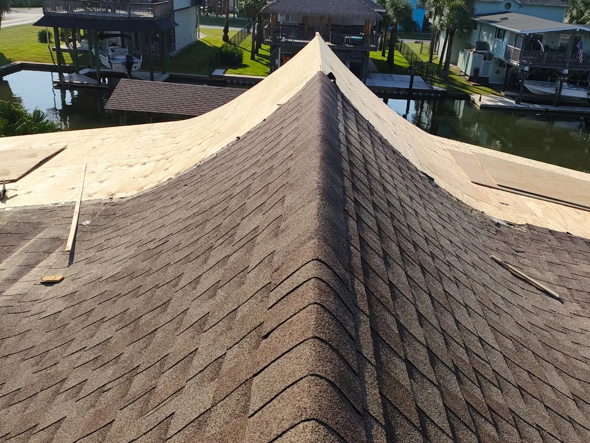 Asphalt shingle roof under installation with hip and ridge shingles set along the peak