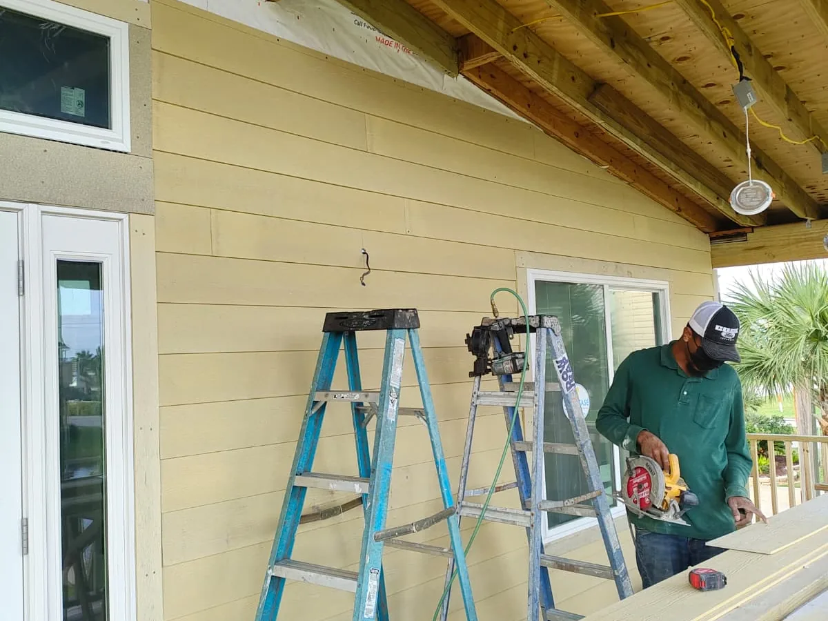 Yellow lap siding being installed on an exterior wall