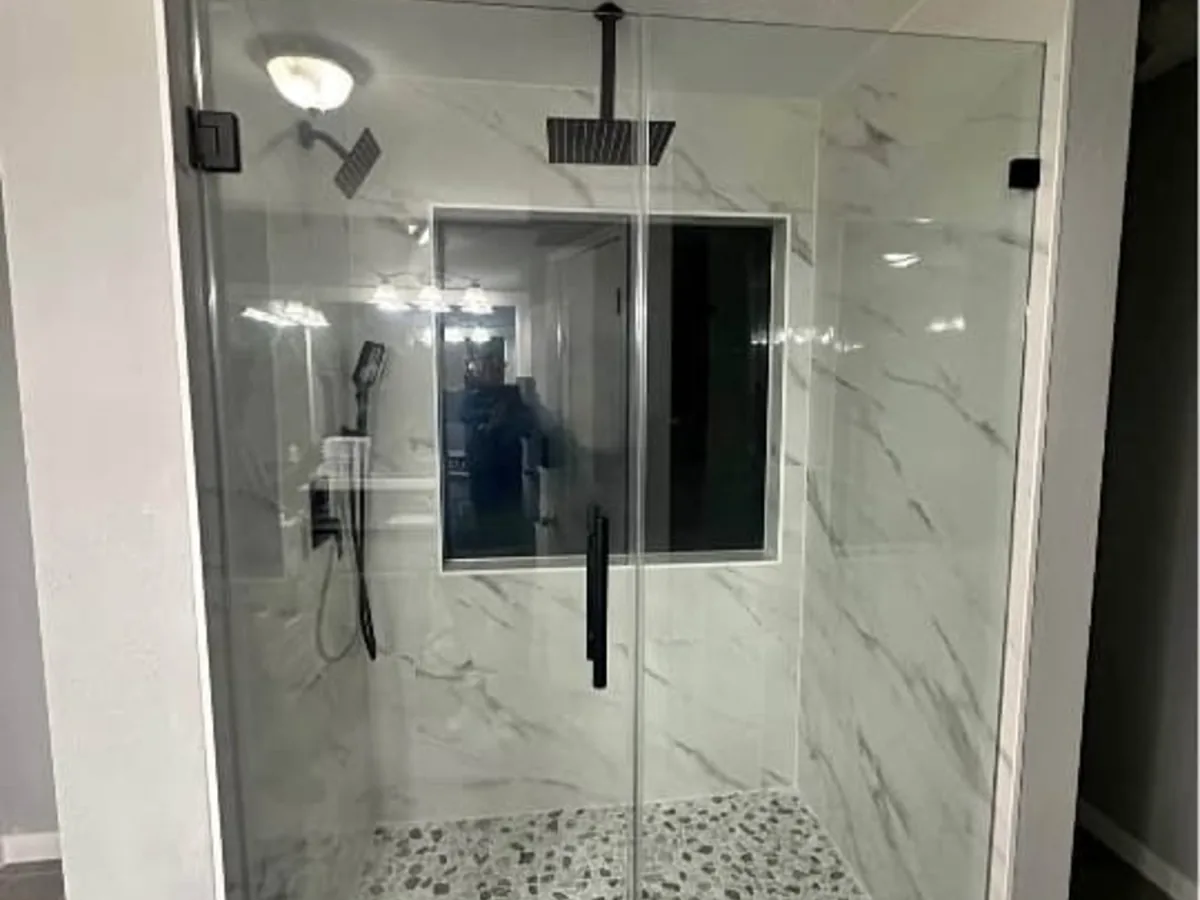 Remodeled bathroom with a tiled walk in shower, glass door, pebble tile floor, and a vanity